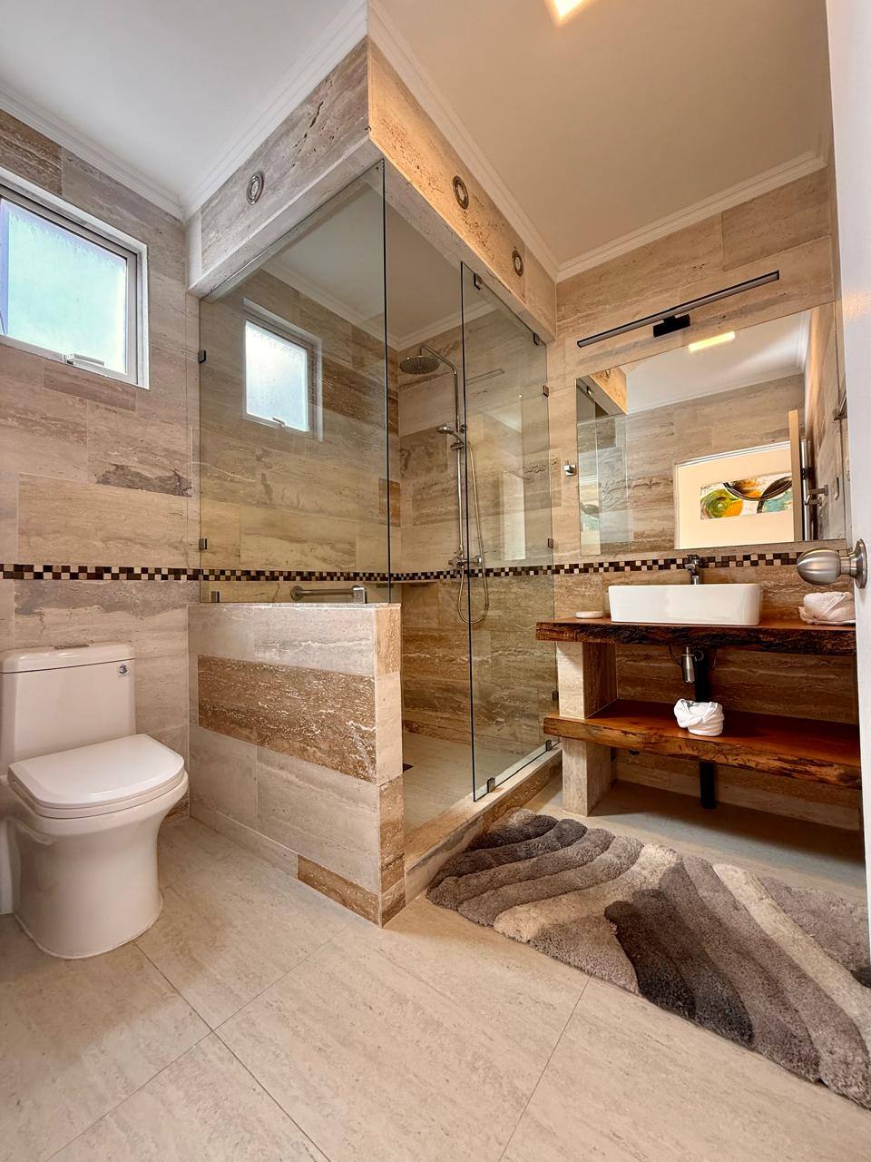 Baño con ducha de vidrio y revestimiento de piedra