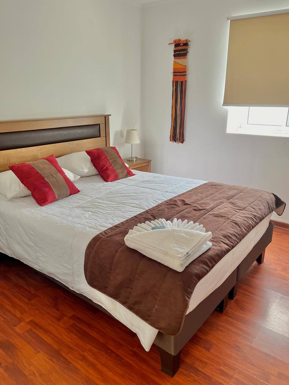 Cama con cojines rojos y cubrecama café