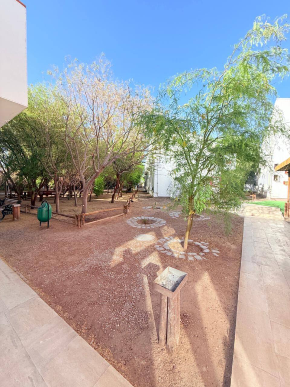 Jardín con árboles y bancas junto a las habitaciones