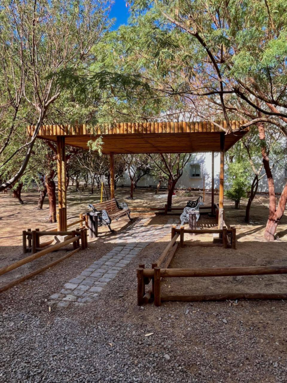 Pérgola de madera con bancas en el jardín del hotel
